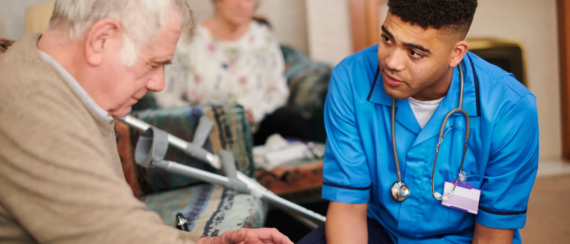 A Healthcare student in a Placement role assisting an Elderly man in a caring environment.