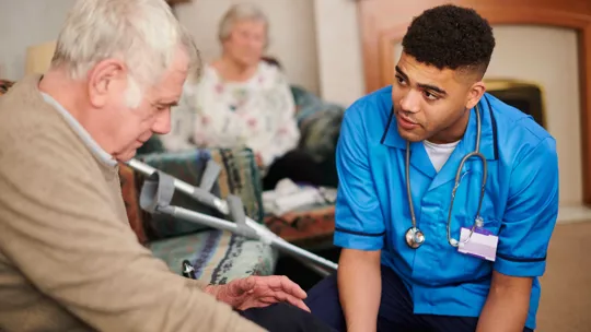 A Healthcare student in a Placement role assisting an Elderly man in a caring environment.