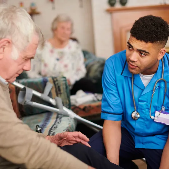 A Healthcare student in a Placement role assisting an Elderly man in a caring environment.
