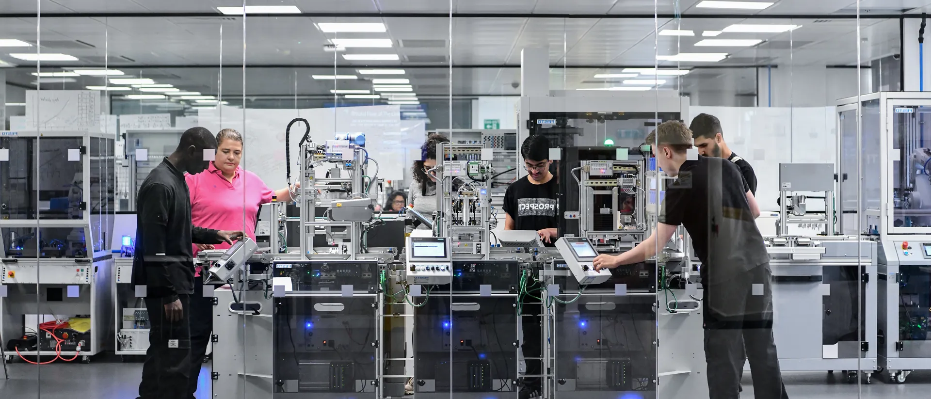 Lecturer demonstrates industrial machinery to students during a practical engineering lab session in a modern laboratory