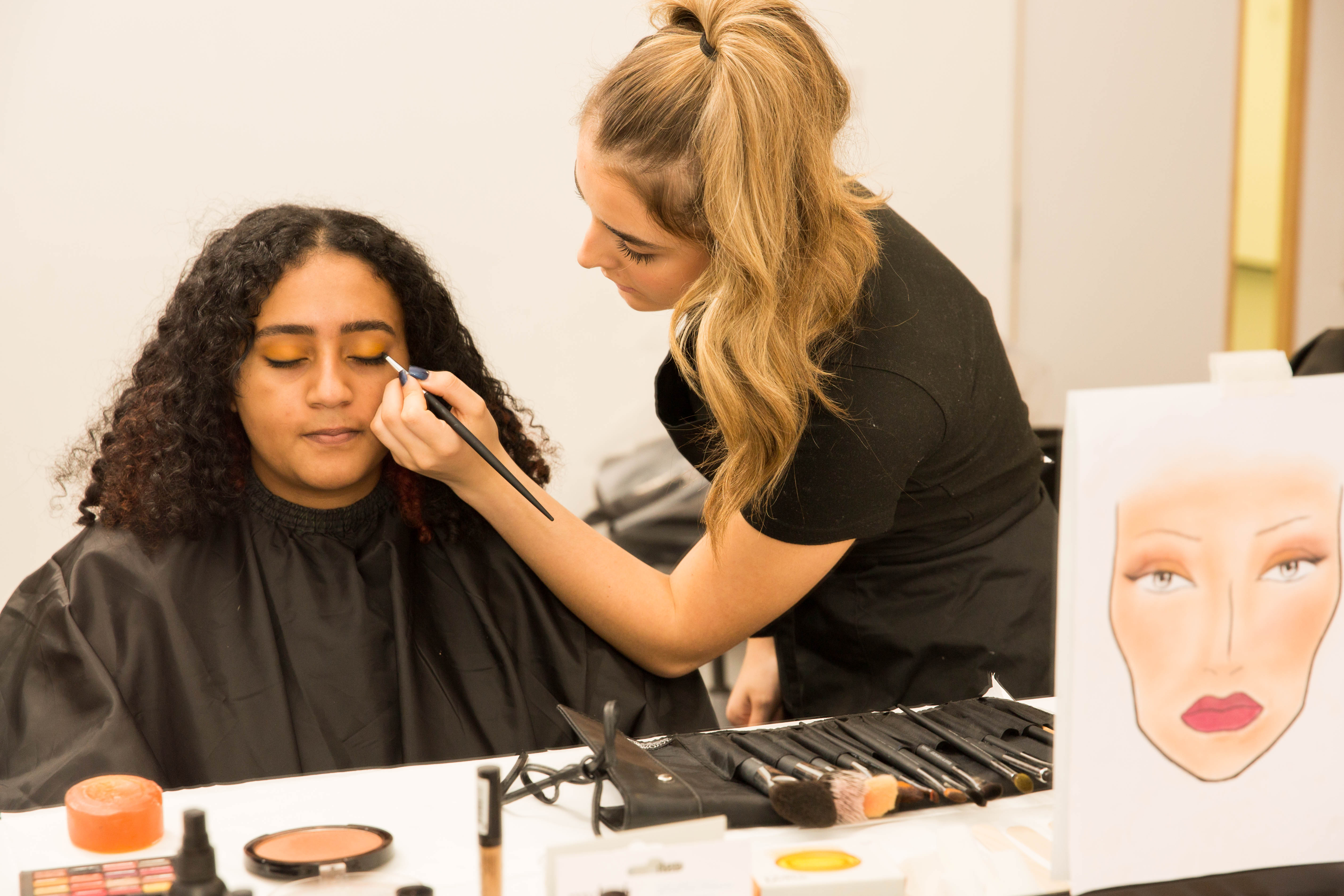 A student applying make-up on a client.