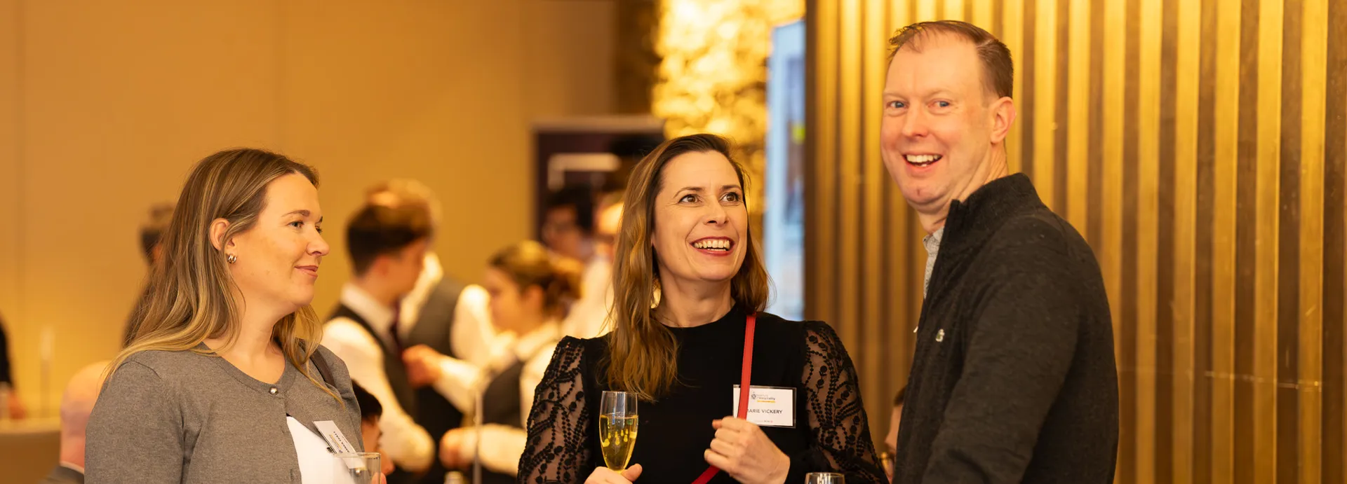 Two females and one male standing talking and smiling