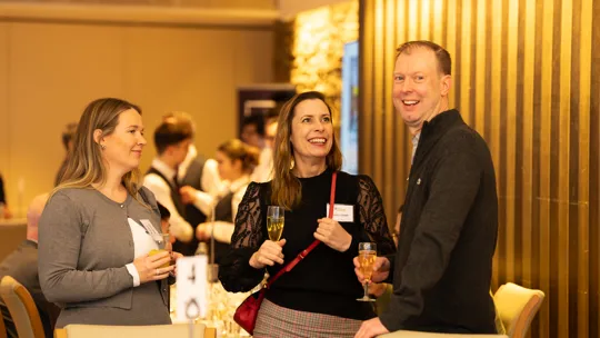 Two females and one male standing talking and smiling