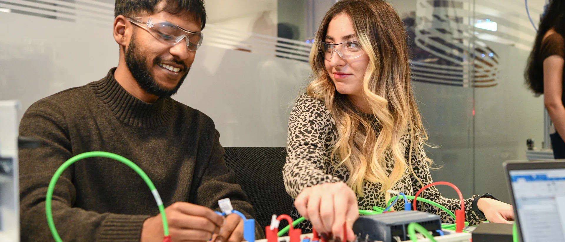 Two student connecting wires on an electric board.