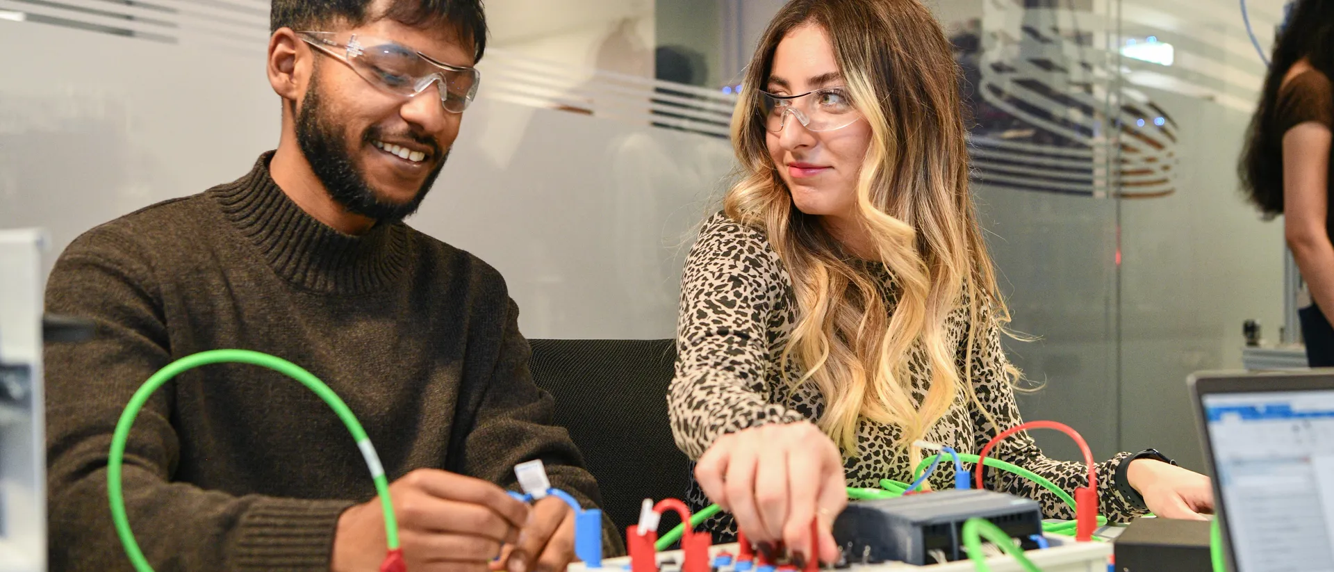 Two student connecting wires on an electric board.