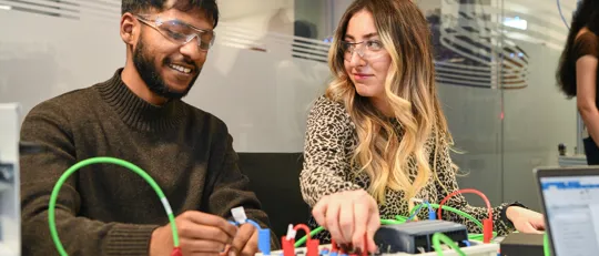 Two student connecting wires on an electric board.
