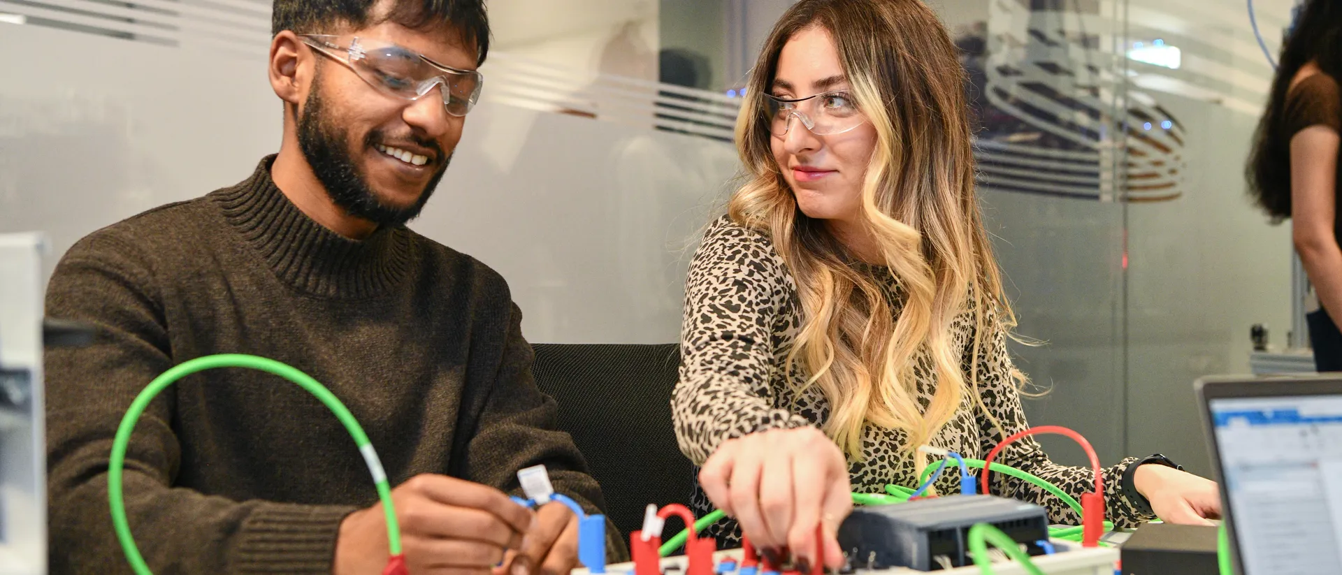 Two student connecting wires on an electric board.