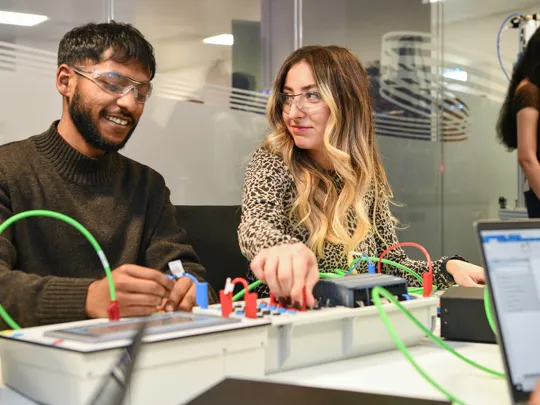 Two student connecting wires on an electric board.