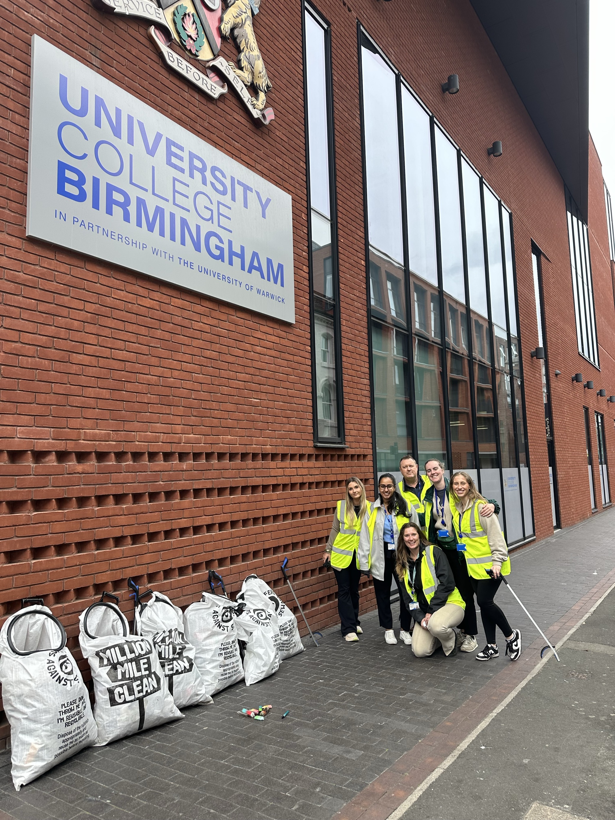 Image of a group of students and staff with the bags they got from a litter pick