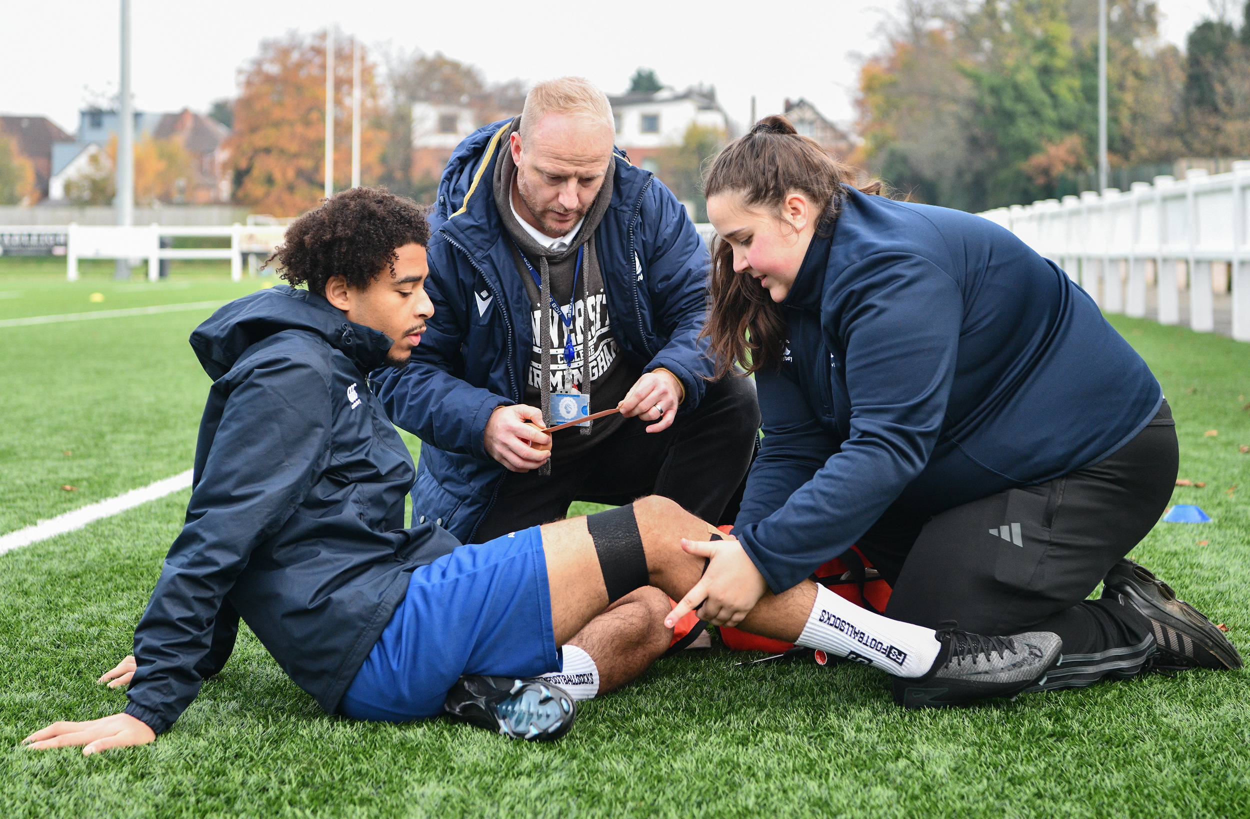 Student and staff member on football field assisting sport injury