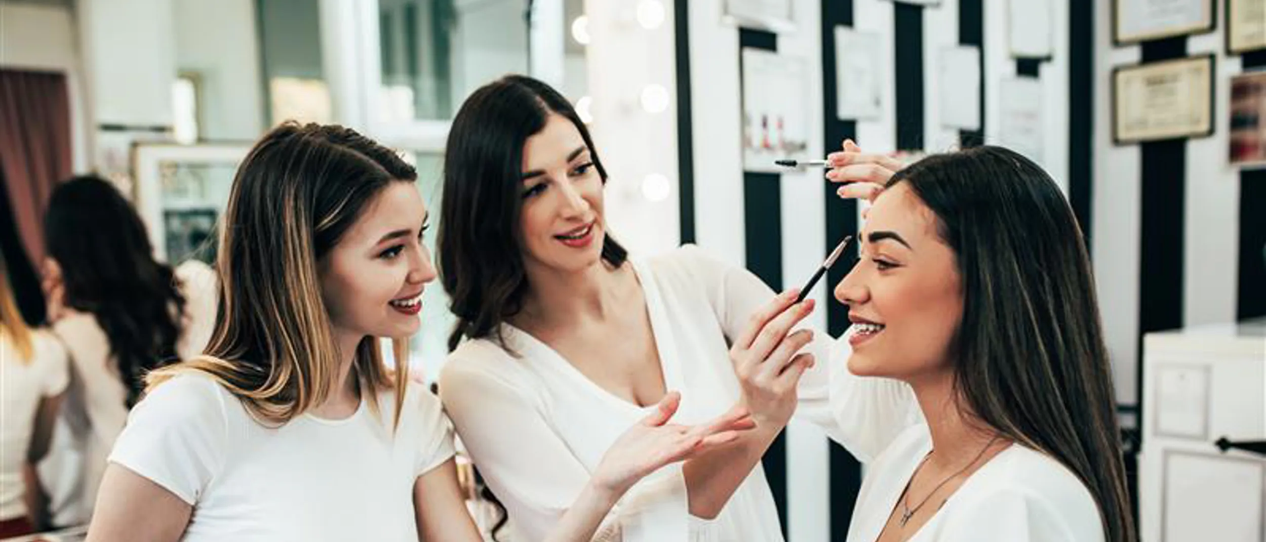a woman training a younger person how to create a look on a model