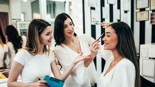 a woman training a younger person how to create a look on a model