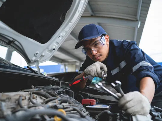 Young mechanic working on a car engine.
