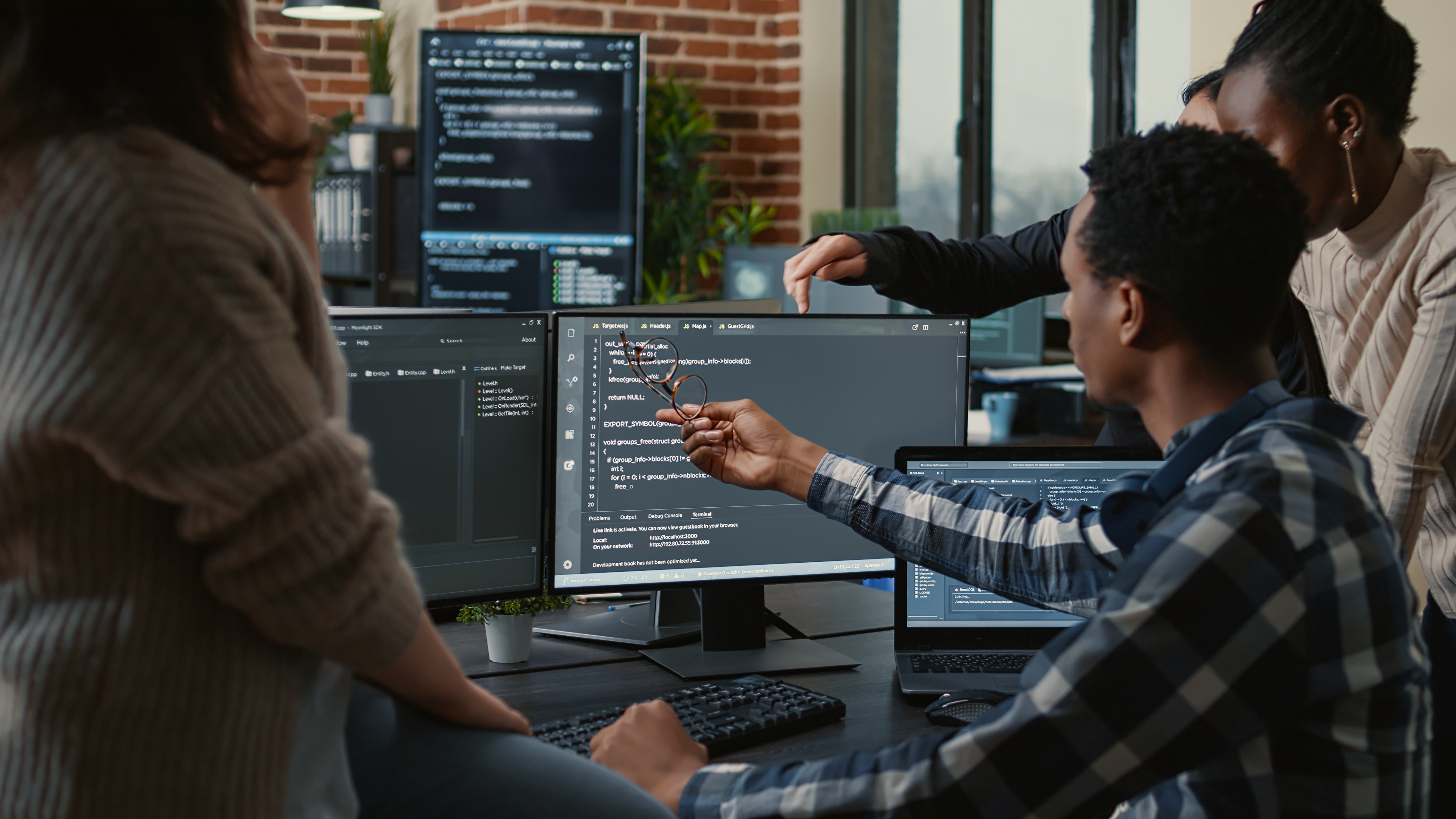Group of young people problem solving software at a computer.