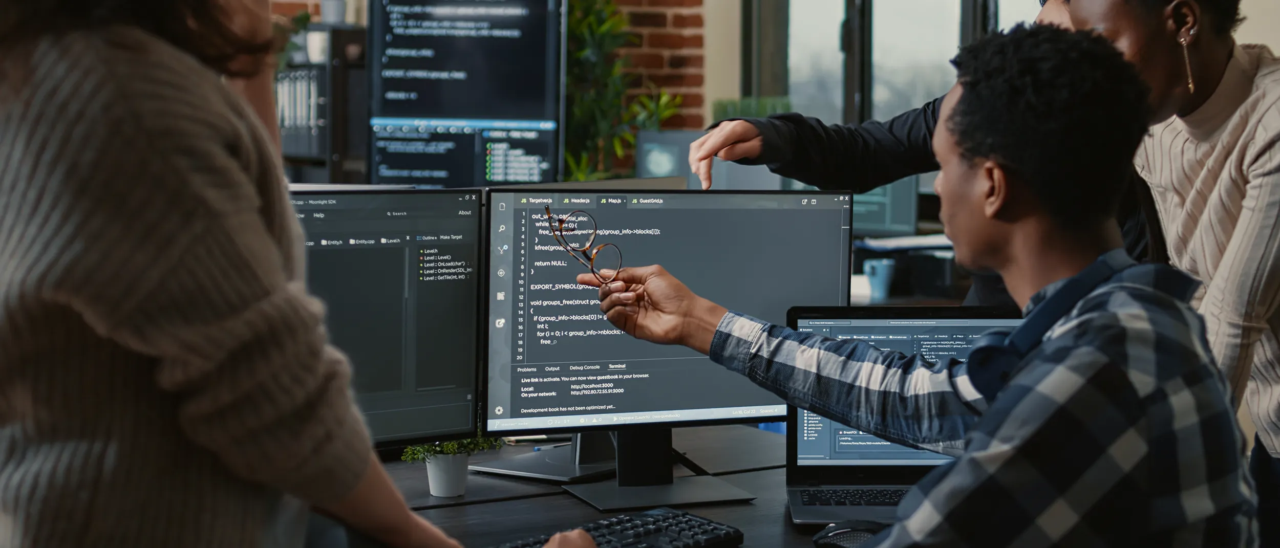 Group of young people problem solving software at a computer.