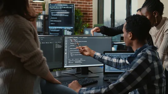 Group of young people problem solving software at a computer.