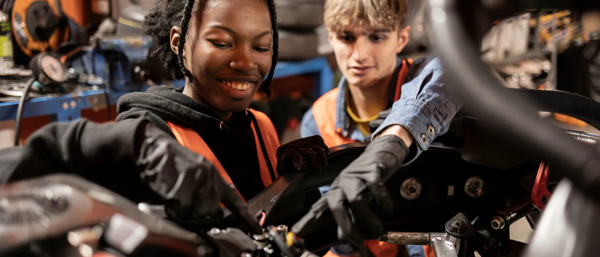 Two young mechanics, one male and one female, working together on engine repairs