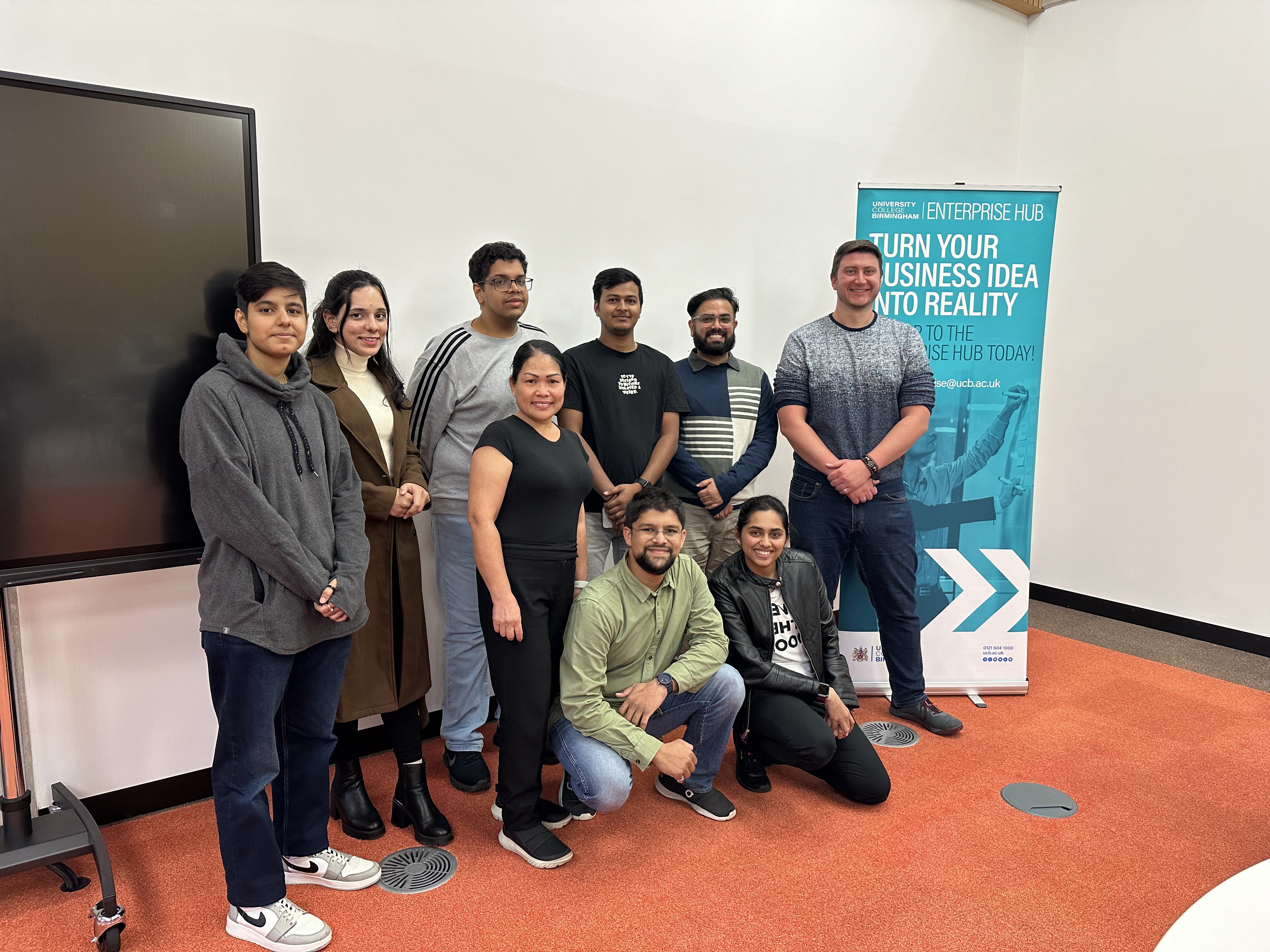 Group of higher education students stood together smiling with a guest speaker and the enterprise hub manager.
