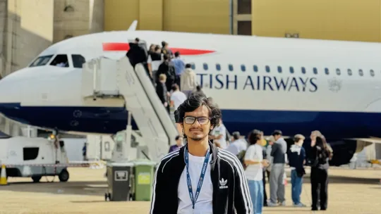 An engineering male student stood in front of a British Airways plane