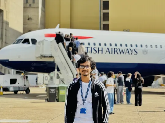 An engineering male student stood in front of a British Airways plane