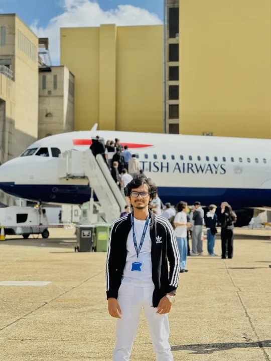 An engineering male student stood in front of a British Airways plane