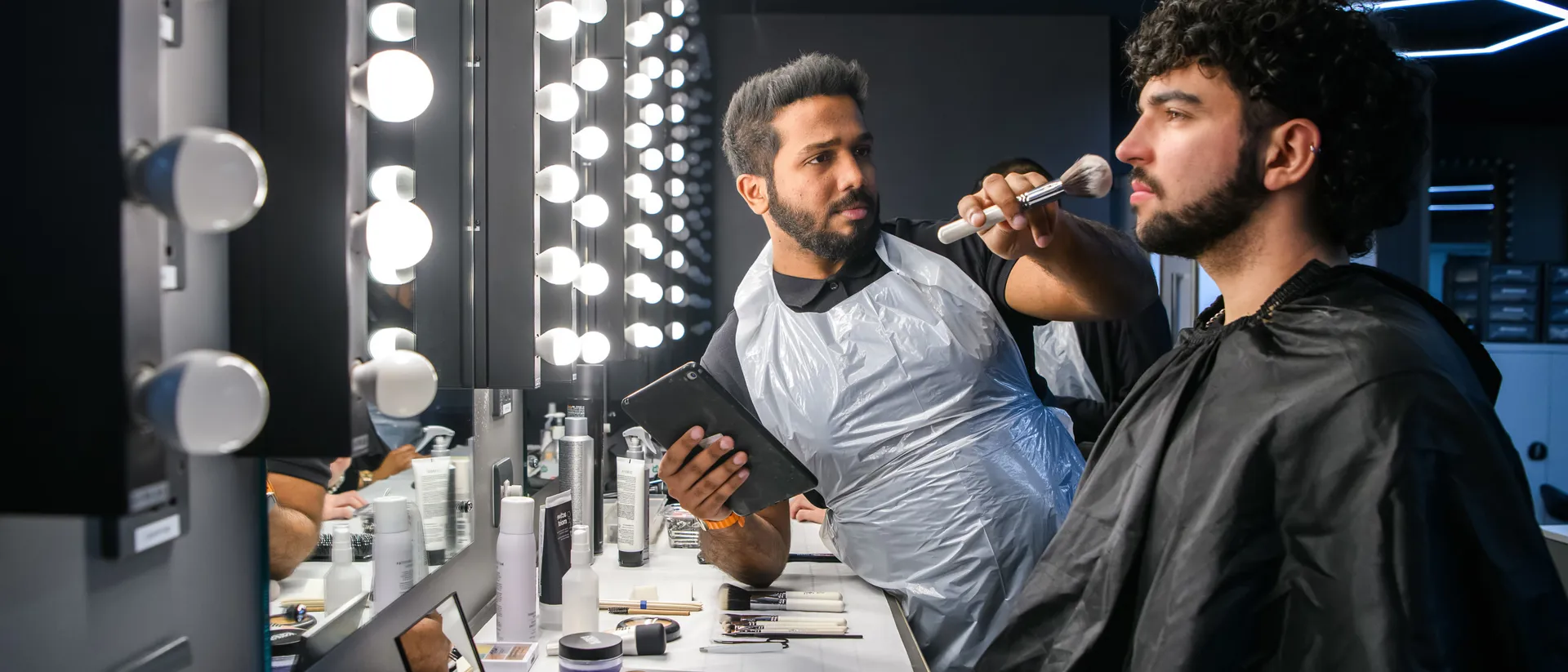 Male student apply make-up to a male model