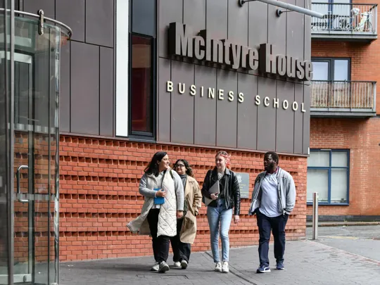 Group of students walking up to our McIntyre campus the business school.