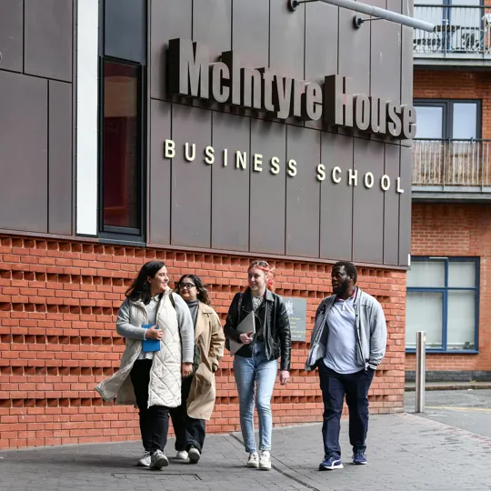 Group of students walking up to our McIntyre campus the business school.