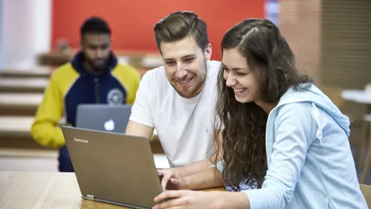 Students at University College Birmingham working on laptops in the cafeteria in McIntyre House