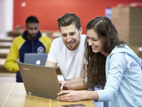 Students at University College Birmingham working on laptops in the cafeteria in McIntyre House