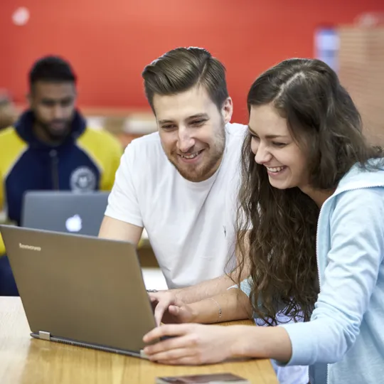 Students at University College Birmingham working on laptops in the cafeteria in McIntyre House