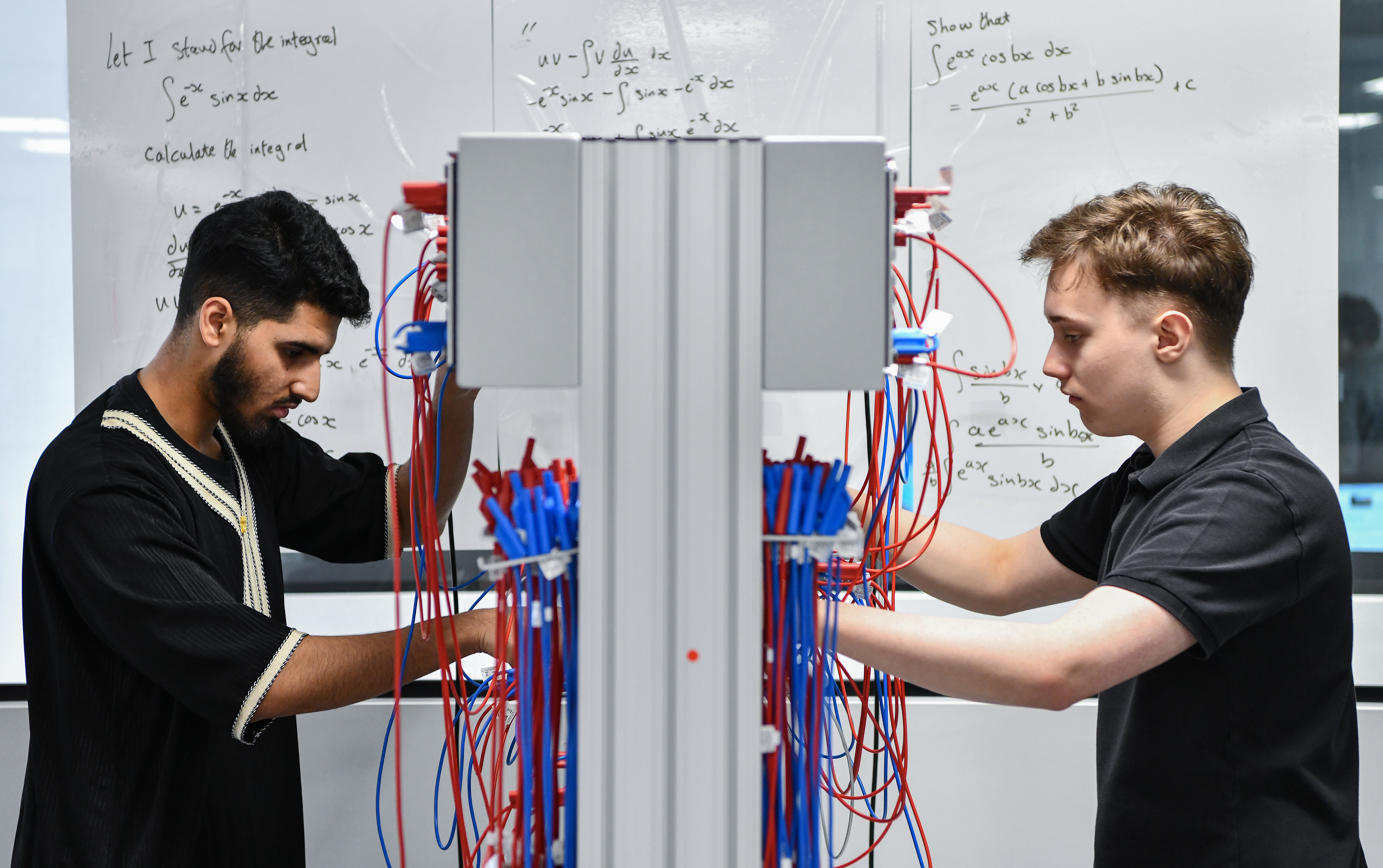 Two male student wiring up a board.