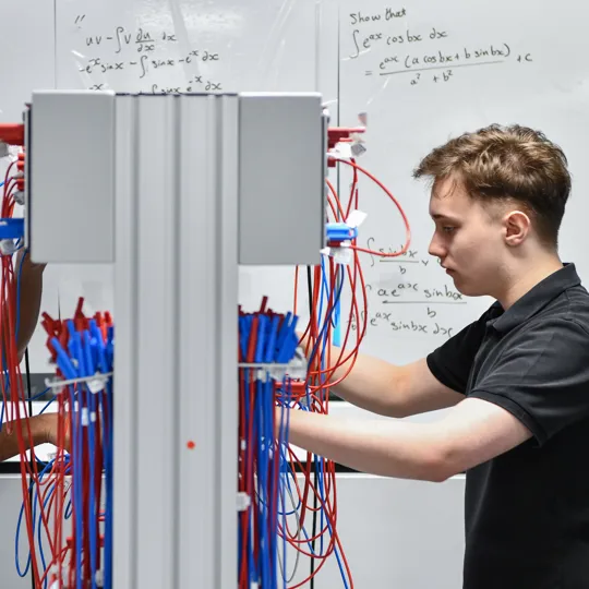 Two male student wiring up a board.