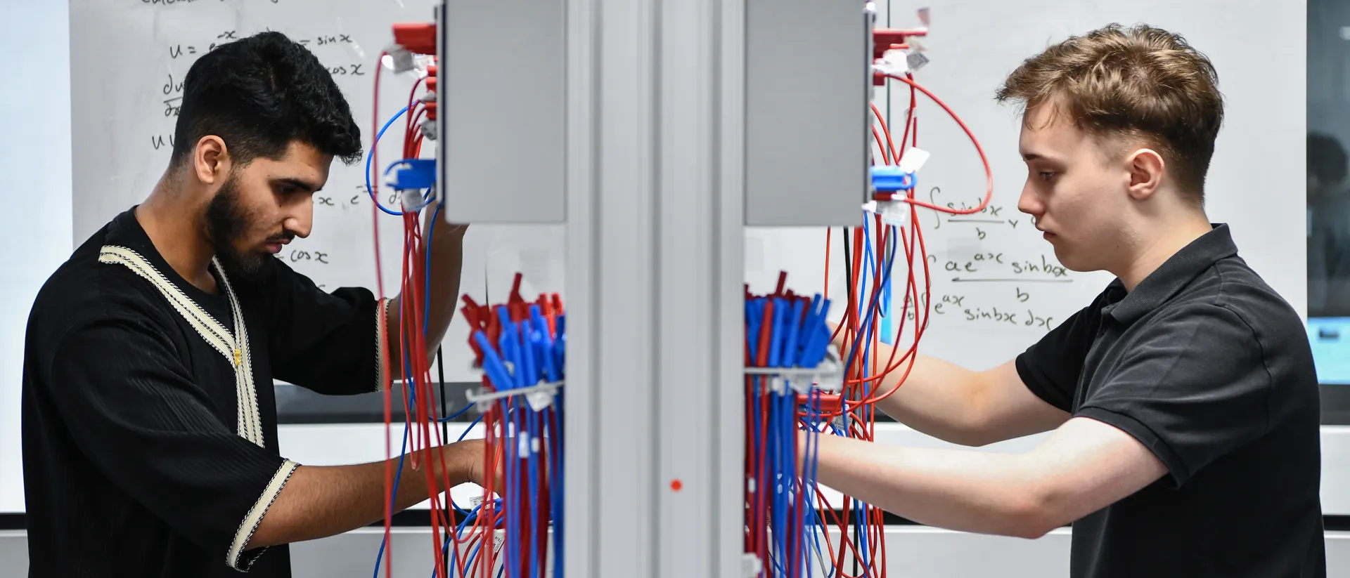 Two male student wiring up a board.