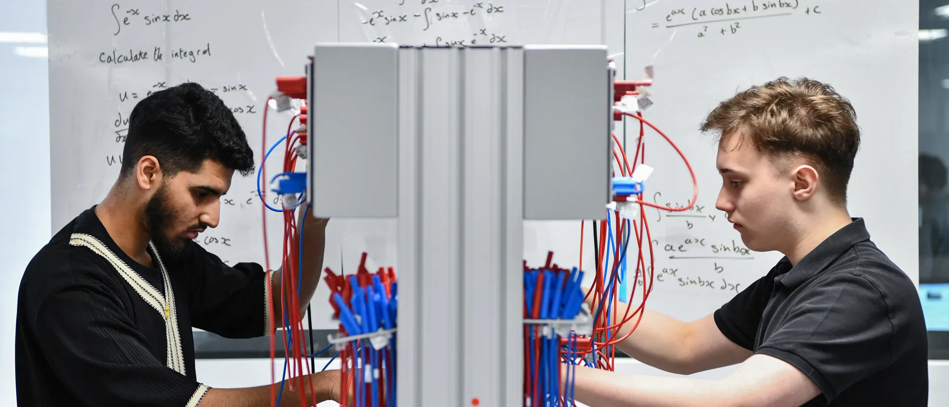 Two male student wiring up a board.
