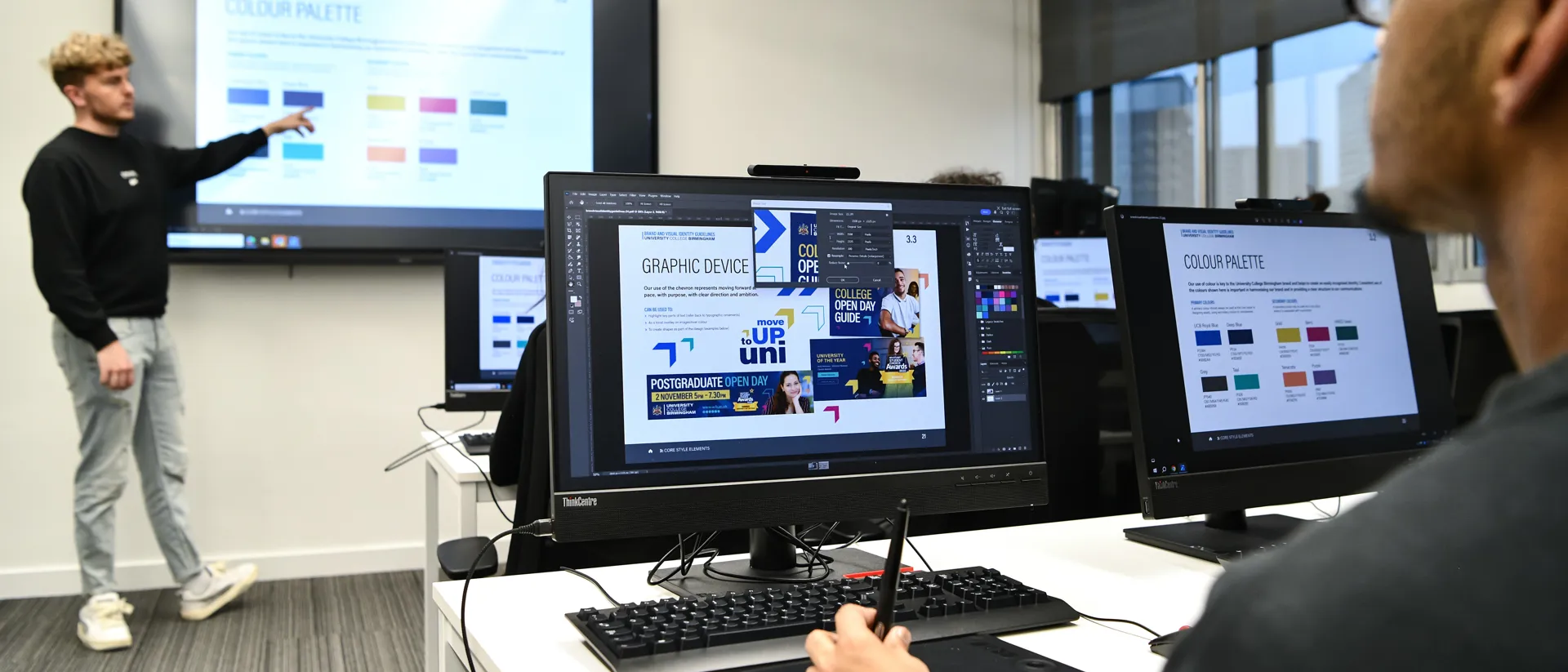 Student working on a computer looking at brand guidelines while in a presentation.