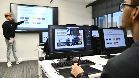 Student working on a computer looking at brand guidelines while in a presentation.
