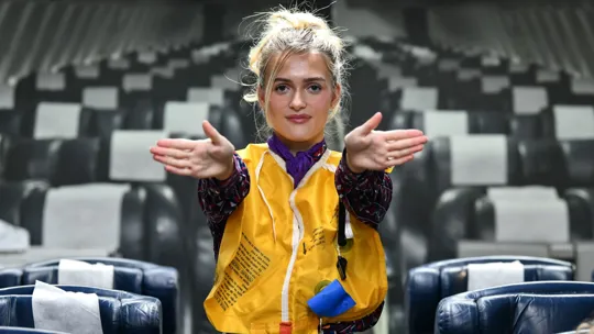 Female student in a mock airplane with life vest pointing to exits.